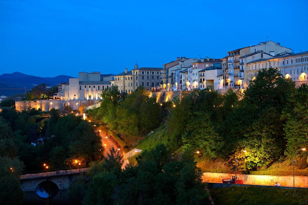 Vista nocturna de las murallas de Pamplona coronadas por casitas de colores